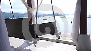 Empty white canopy swing or patio swing by the beach.