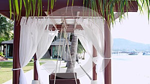 Empty white canopy swing or patio swing by the beach. slow motion. 3840x2160