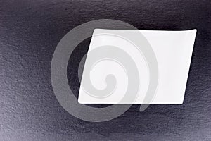 Empty white ceramic bowl on black slate plate