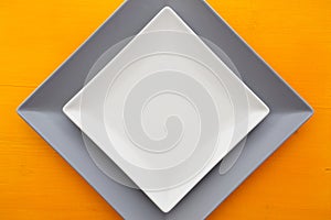 Empty white ceramic dish on over orange wooden table