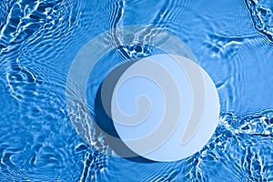 Empty white circle podium on transparent blue water background with copy space