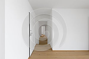 Empty white corridor with open doors