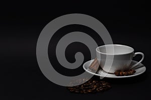 Empty white cup and saucer, coffee beans, cinnamon sticks, anise