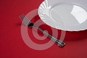 Empty white dinner plate with silver fork and Dessert Tablespoon isolated on red tablecloth background with copy space. Table Set