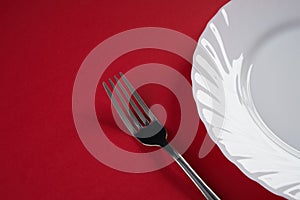 Empty white dinner plate with silver fork and Dessert Tablespoon isolated on red tablecloth background with copy space. Table Set