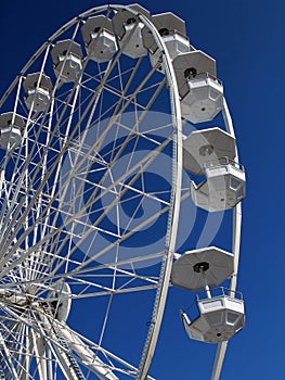 Empty white Ferris wheel spinning on blue sky background