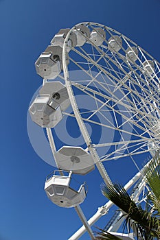 Empty white Ferris wheel spinning on blue sky background