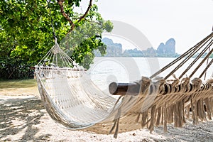 Empty white hammock at Krabi Railey beach overlooking the harbour and mountains, Thailand