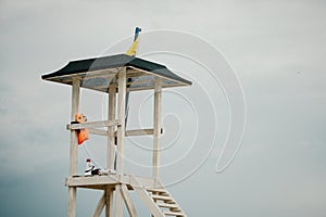 Empty white lifeguard tower with a yellow flag on the beach in windy weather. Beach lifeguard tower with yellow flag