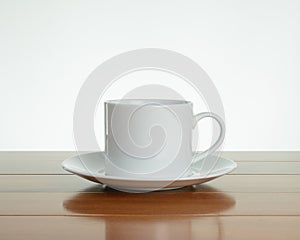 Empty white mug with saucer on wood