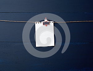 Empty white notebook paper sheet hanging on decorative holiday clothespin