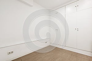 Empty white painted room with reddish marble floors and fitted wardrobes