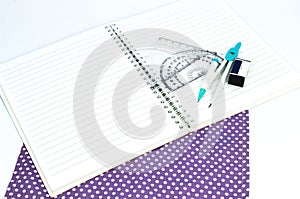 Empty white paper notebook with ruler, protractor, angle, triangle, square on the white background.