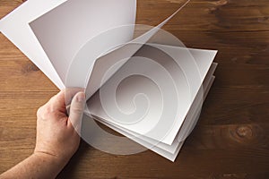 Empty white paper for notes, notebook, diary, booklet, organizer in hand on a wooden table.