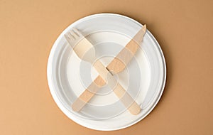 empty white paper plate and wooden knife and fork