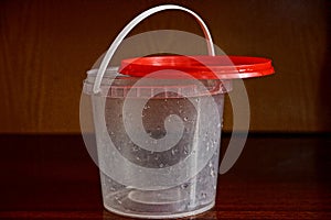 Empty white plastic bucket with a red lid