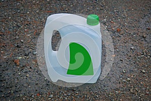 An empty white plastic canister stands on the ground close-up.