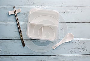Empty white plastic food container with spoon and chopstick
