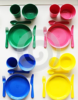 Empty white plastic plate, cup, fork and spoon over white background with copy space. Dining set of plastic cutlery on