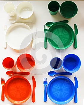 Empty white plastic plate, cup, fork and spoon over white background with copy space. Dining set of plastic cutlery on