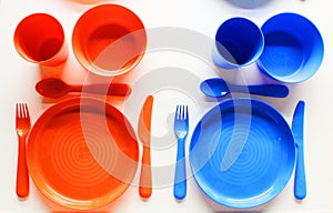 Empty white plastic plate, cup, fork and spoon over white background with copy space. Dining set of plastic cutlery on