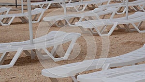 Empty white plastic sun loungers on the beach. Beach vacation without people.