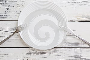 Empty white plate with appliances on a numbed table. Top view