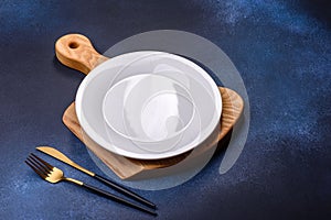 Empty white plate on blue background table. Flat lay