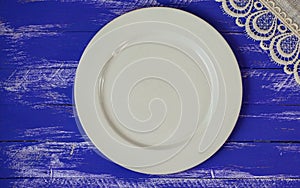 Empty white plate on a blue shabby wooden surface