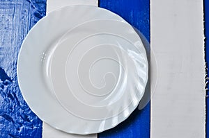 Empty white plate on blue and white wooden background