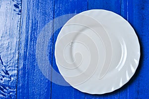 Empty white plate on blue and white wooden background