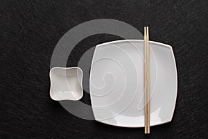 Empty white plate with chopsticks and a gravy boat on a dark background. Japanese food style. Top view with copy space