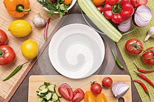 Empty white plate and different fresh vegetables and  ingredients for cooking salad. Diet, fasting, vegan, vegetarian food