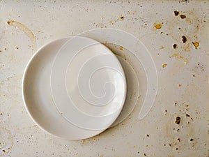 Empty white plate on dirty stained board. Attrition concept.