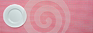 Empty white plate on red checkered tablecloth background, banner