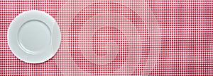 Empty white plate on red checkered tablecloth background, banner photo