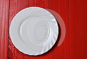 Empty white plate on red wooden background