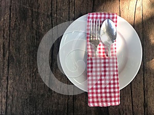 Empty white plate with silverware, spoon and fork and red scoth