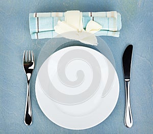 Empty white plate with silverware on wooden table