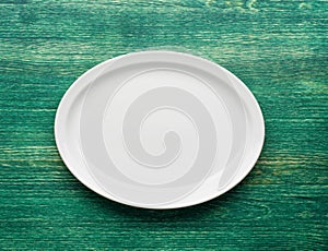 Empty white plate on wooden green table