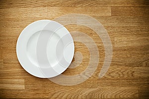 Empty white plate on wooden table