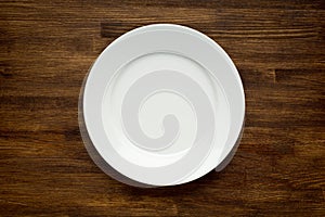 Empty white plate on wooden table