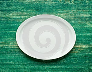 Empty white plate on wooden table. Flat lay.