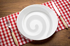 Empty white plate on wooden table over red grunge