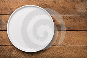 Empty white plate on a wooden table top, background or backdrop