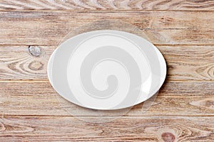 Empty white plate on wooden table. top view