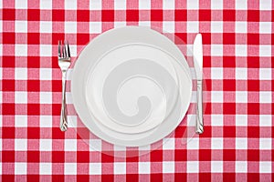 Empty white plates on checkered tablecloth