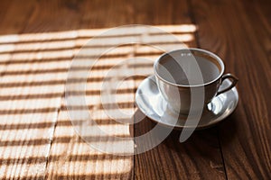 Empty white porcelain cup with saucer, on a wooden table, closeup.