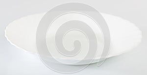 Empty white porcelain plate on white table surface