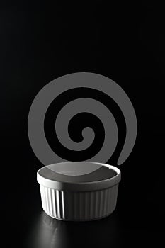 Empty white Ramekin on black background with copy space